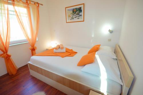ein Schlafzimmer mit einem Bett mit orangefarbenen Kissen und einem Fenster in der Unterkunft Vacation home Vesna in Bribir