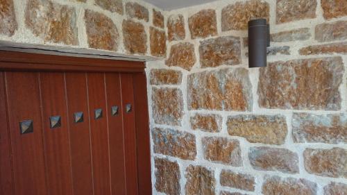 a garage door and a brick wall with a black pipe at Stone house with seaview in Nea Potidaea