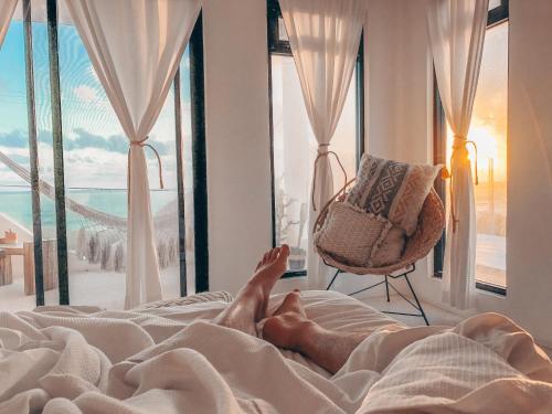 a person laying on a bed with a window at Icaco Island Village - Adults Only in Isla Mujeres