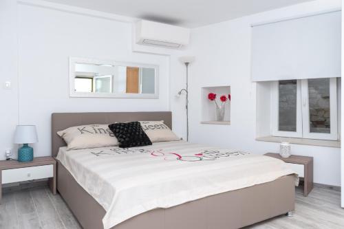 une chambre blanche avec un grand lit et deux fenêtres dans l'établissement Bounty Apartments, à Šibenik