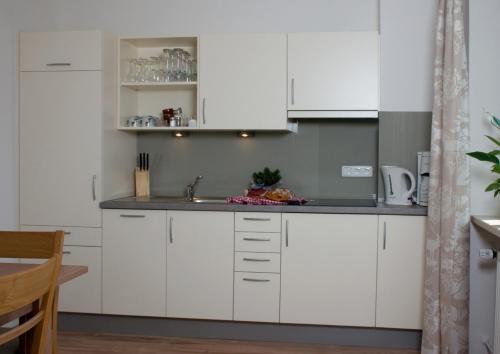 a kitchen with white cabinets and a sink at Hölbinger Alm - Apartments in Anger