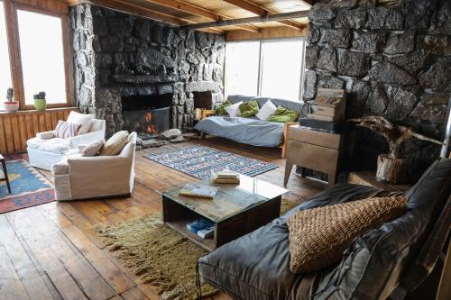 sala de estar con sofá y pared de piedra en Cordillera Hostel en Farellones