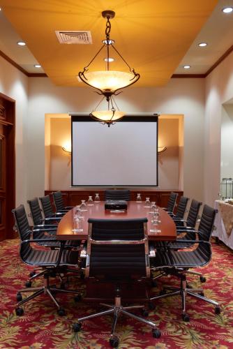 a conference room with a table and chairs and a projection screen at Suites las Palmas, Hotel & Apartments. in San Salvador
