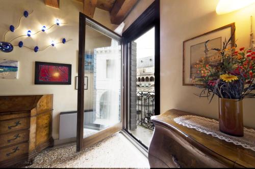 Cette chambre est dotée d'une porte coulissante en verre avec un vase de fleurs. dans l'établissement PadovaResidence Apartments - vista Piazza delle Erbe e Palazzo della Ragione, à Padoue