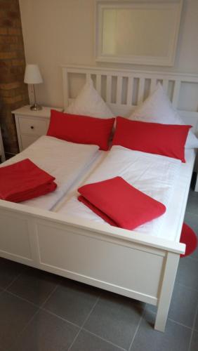 a white bed with red pillows on it at Haus Harzland in Wernigerode