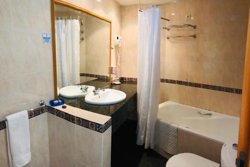 uma casa de banho com um lavatório, uma banheira e um WC. em Golden Park Hotel em Luanda
