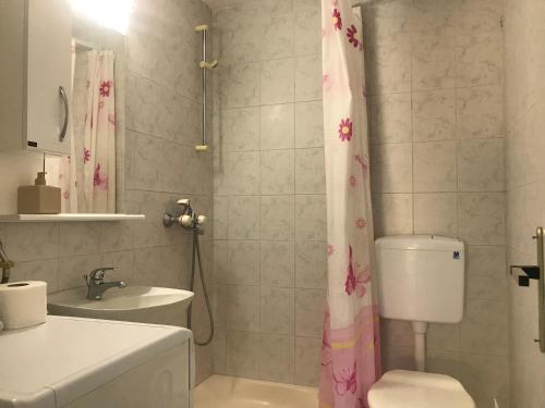 a bathroom with a pink shower curtain and a toilet at Apartmani Konjević in Herceg-Novi