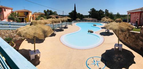 ein Pool mit Sonnenschirmen in einem Resort in der Unterkunft Hotel Pedra Niedda in Budoni