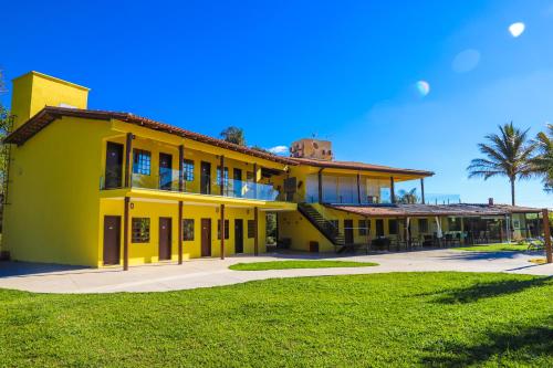 a large yellow building with a lawn in front of it at Pousada Cateto - Zona Rural in Capitólio