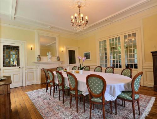ein Esszimmer mit Tisch und Stühlen und einem Kronleuchter in der Unterkunft Manoir Les Brieux in Plélan-le-Grand