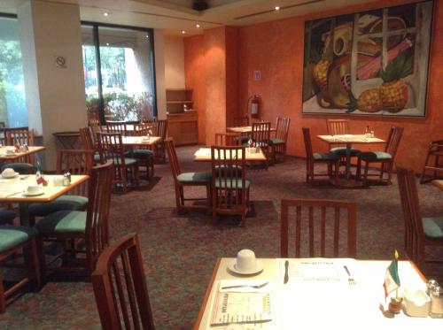 a restaurant with tables and chairs and a painting on the wall at Hotel Sevilla in Mexico City