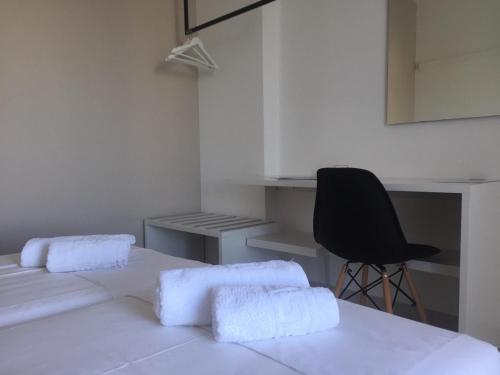 a white room with two beds and a black chair at Galini Rooms & Apartments in Finikas