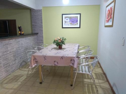 einen Tisch mit Stühlen und eine Vase mit Blumen darauf in der Unterkunft Castanheiras 3 Quartos in Guarapari