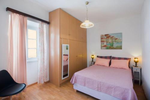 a bedroom with a pink bed and a window at Andrew's Old Town Apartment in Corfu Town
