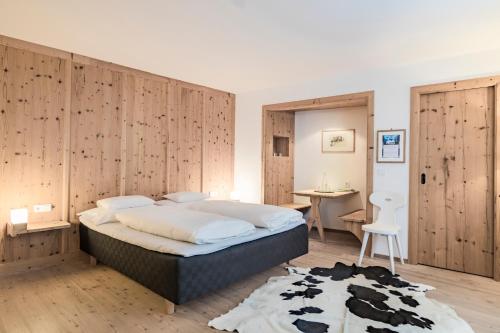 a bedroom with a large bed with a wooden wall at Hotel Drumlerhof in Campo Tures