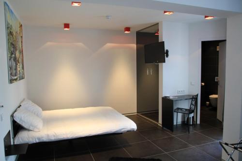 a bedroom with a bed and a desk and a television at Hotel Grey in Luxembourg