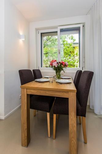 un tavolo in legno con sedie e un vaso di fiori sopra di Nest - Neptun Studio at Seefeld a Zurigo