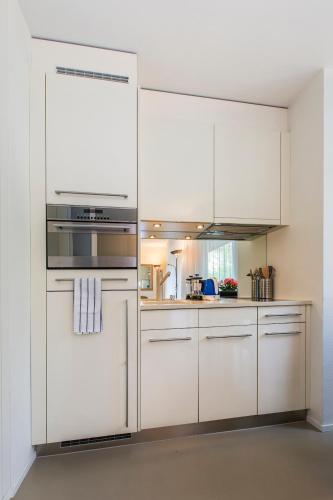 a kitchen with white cabinets and a stove top oven at Nest - Neptun Studio at Seefeld in Zürich