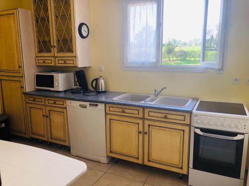 a kitchen with a sink and a stove and a microwave at LE PETIT MARAIS in Clais