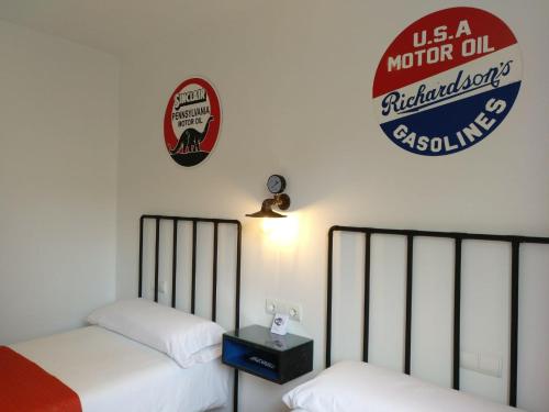 two beds in a room with a usa motor oil sign at PENSION ROSELLA in O Pedrouzo