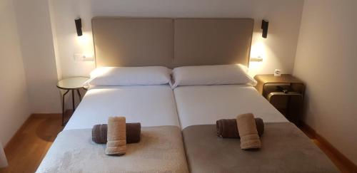 a bedroom with a large white bed with two towels at PENSION ROSELLA in O Pedrouzo