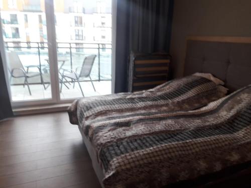 een slaapkamer met een bed en een balkon met stoelen bij APARTAMENT W BEL MARE in Międzyzdroje