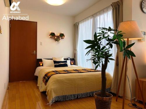 a bedroom with a bed and a potted plant at Alphabed Takamatsustation 301 / Vacation STAY 38150 in Takamatsu