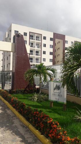 a sign in front of a building with palm trees at Apart Varanda do Poxim in Aracaju