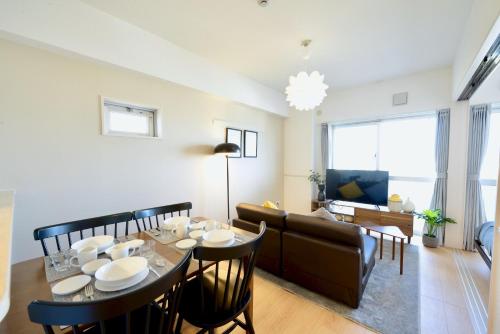 a dining room and living room with a table and chairs at Allstay CHIBANA in Okinawa City