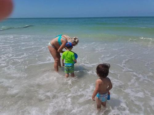 a woman and two children standing in the water at the beach at The Beach on Longboat Key in Longboat Key