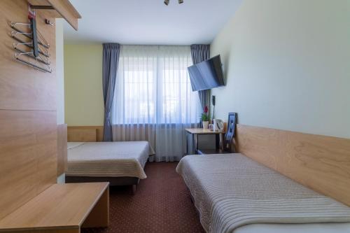 a hotel room with two beds and a tv at Villa Aida pokoje gościnne in Gdańsk