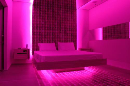 a bedroom with a bed in pink lighting at Lush Motel Ipiranga in Sao Paulo