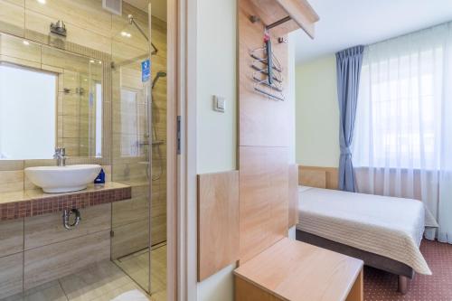 a bathroom with a shower and a sink and a bed at Villa Aida pokoje gościnne in Gdańsk