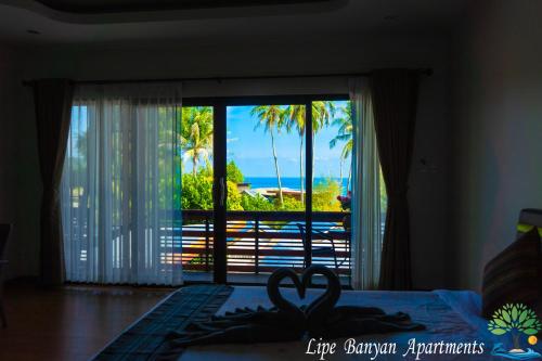 a bedroom with a bed with a view of the ocean at Lipe Banyan Apartments in Ko Lipe