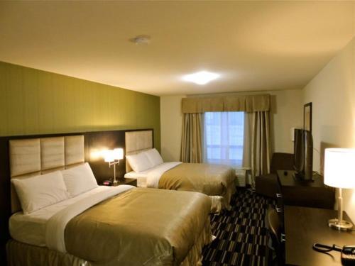 a hotel room with two beds and a television at Western Star Inn & Suites Esterhazy in Esterhazy