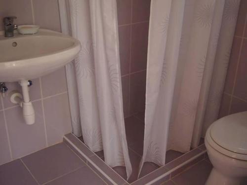 a bathroom with a white shower curtain and a sink at DéeL apartman in Nyíregyháza