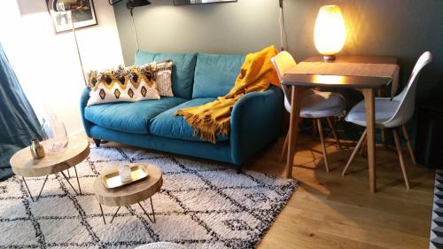 un salon avec un canapé bleu et une table dans l'établissement Fiquet de Normanville pour votre bien être en plein coeur historique, à Rouen