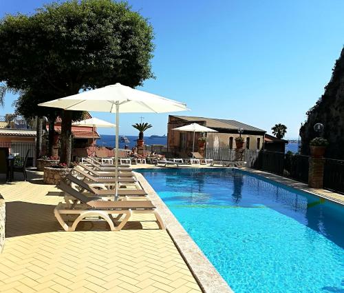 a swimming pool with lounge chairs and an umbrella at Hotel Corallo in Taormina