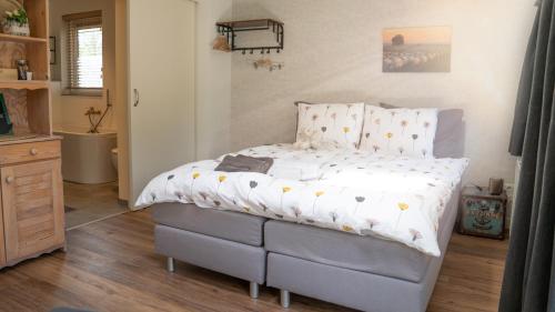 een slaapkamer met een bed met een wit dekbed bij De Anselier in Ansen