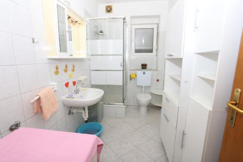a white bathroom with a sink and a toilet at Apartman Luna in Dugi Rat