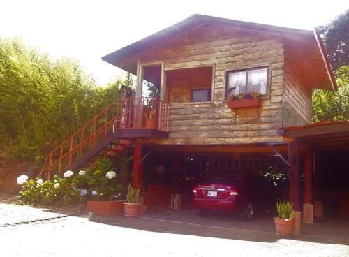 a house with a car parked in front of it at Hotel Chalets Los Volcanes in Alajuela City