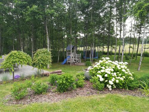 a garden with a playground and flowers in the grass at Wiejska Chata in Szwalk