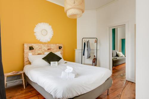 sypialnia z dużym białym łóżkiem z żółtymi ścianami w obiekcie NOCNOC-Grand Place-La Perle w Lille