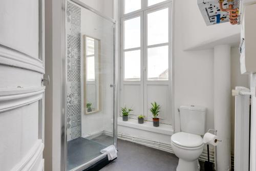 La salle de bains est pourvue de toilettes et d'une douche avec des plantes en pot. dans l'établissement NOCNOC-Grand Place-La Perle, à Lille