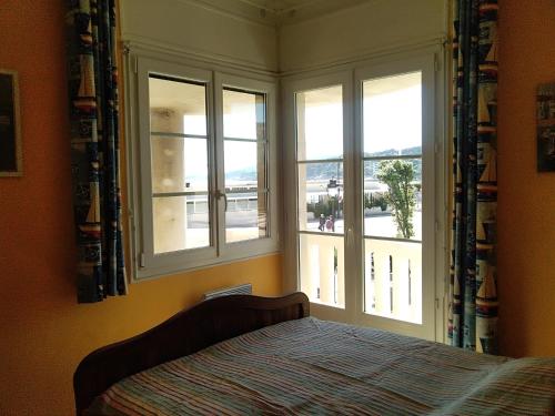 une chambre avec un lit et deux fenêtres dans l'établissement LA PLAGE, à Cassis