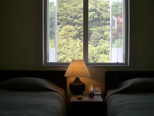 a bedroom with two beds and a lamp and two windows at Gallery Court Ofa Atu in Kawazu