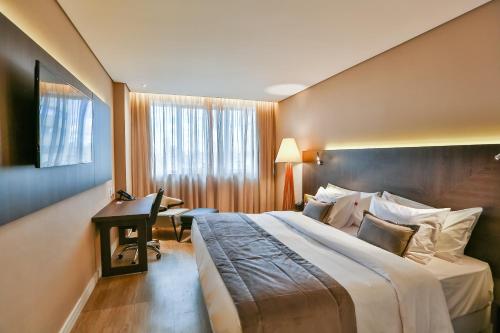 a hotel room with a large bed and a desk at Transamerica Collection Goiania in Goiânia