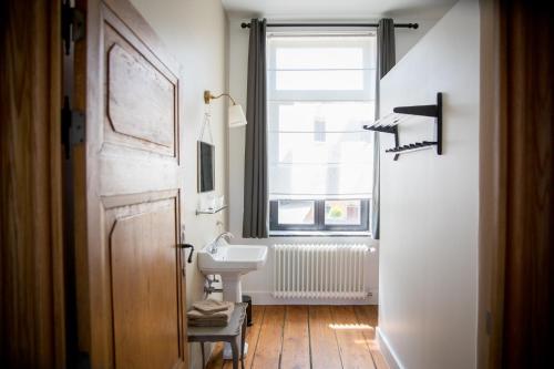 La salle de bains est pourvue d'un lavabo et d'une fenêtre. dans l'établissement La Maison du Passavant (Gîte à la ferme), à Genappe