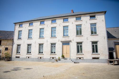 a large white brick building with a yellow door at La Maison du Passavant (Gîte à la ferme) in Genappe