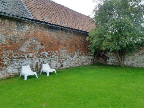 two white chairs sitting next to a brick wall at La Maison du Passavant (Gîte à la ferme) in Genappe